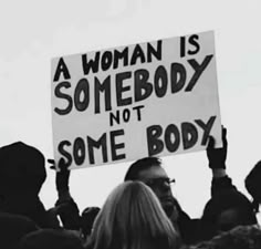 a woman is holding a sign that says, a woman is somebody not some body