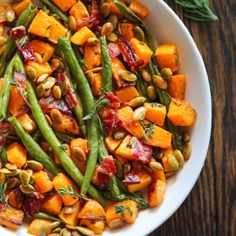 a white bowl filled with green beans and sweet potatoes