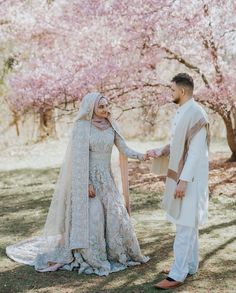 a bride and groom holding hands in front of cherry blossom trees