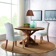 a dining room table with two chairs and a vase on the rug in front of it