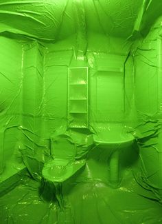 a green bathroom with toilet and sink covered in plastic