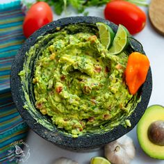 a bowl filled with guacamole surrounded by vegetables