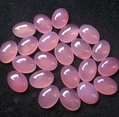 large pink opalite caballons are arranged on a black surface