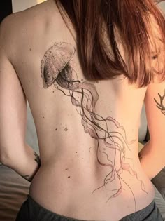 a woman's back with a jellyfish tattoo on her left side ribcage