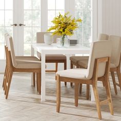 a dining room table with chairs and a vase filled with flowers on top of it