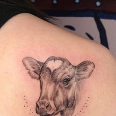 a woman's shoulder with a cow tattoo on it