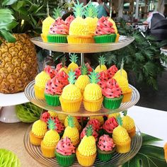 three tiered trays filled with cupcakes and pineapples