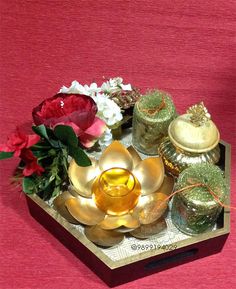 a tray that has some flowers and candles in it on top of a tablecloth