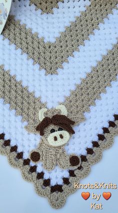 a crocheted baby blanket with a teddy bear on it and a heart hanging from the side