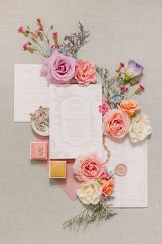 the wedding stationery is laid out with flowers