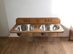 two stainless steel dog bowls are on a wooden stand with the words dog bar written on it