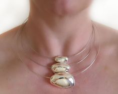 "You may not know, but I was born and raised in the UK and lived there throughout my 20s. My latest collection is titled Pebbles and the inspiration is, you guessed it, pebbles found on the beaches all over Britain. I'm quite partial to a choker. The sterling silver neck wire I use in this necklace is 1mm thick and closes by securely inserting one end into the other. The sterling silver \"pebble\" which is the focal point of the necklace is irresistible to touch. The pebble is 25mm wide x 17mm t Silver Contemporary Necklace, Bob Wire Necklace, Cairn Necklace, Silversmithing Jewelry, Pebble Necklace, Stone Statement Necklace, Necklaces Silver, Jewelry Beach, Silver Choker