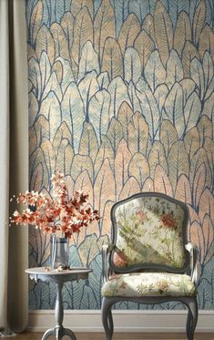 a chair sitting in front of a window next to a vase with flowers on it