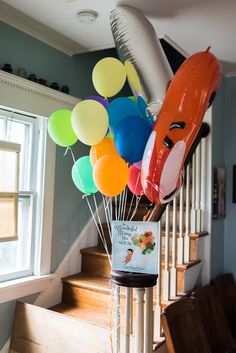 a bunch of balloons in the shape of animals on top of a stair case next to a window