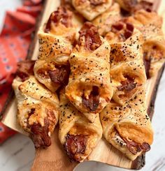 small pastries with pepperoni and other toppings on a wooden cutting board next to a red napkin