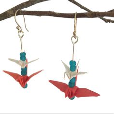 two red and white origami birds hanging from hooks on a branch with blue beads