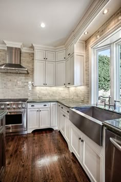 a kitchen with white cabinets and wood floors, stainless steel sink and dishwasher