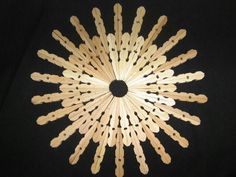 a group of wooden clothes pins arranged in the shape of a star on a black background