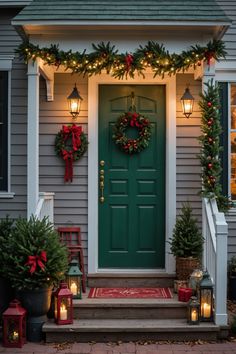 christmas wreaths are hung on the front door of a house with lanterns and candles