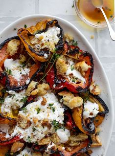 a white plate topped with stuffed peppers covered in cheese and herbs next to a cup of tea