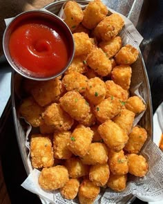 a basket filled with tater tots next to ketchup and dipping sauce