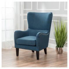 a gray chair next to a potted plant in a white room with wood flooring