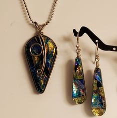 three pieces of jewelry sitting on top of a white table next to a pair of scissors