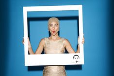 a woman holding up a framed photo with her tongue sticking out in front of her face