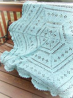 a crocheted blanket sitting on top of a wooden bench