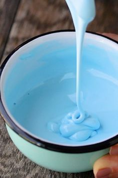 a person pouring blue liquid into a bowl