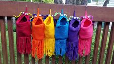 colorful crocheted purses hanging on a wooden fence