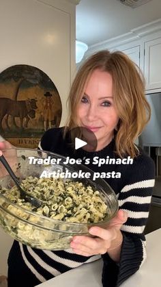 a woman holding a bowl of food in her hands with the caption trader joe's spinach artichoke pasta