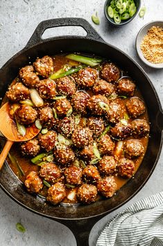 meatballs and vegetables cooking in a skillet with a wooden spoon on the side