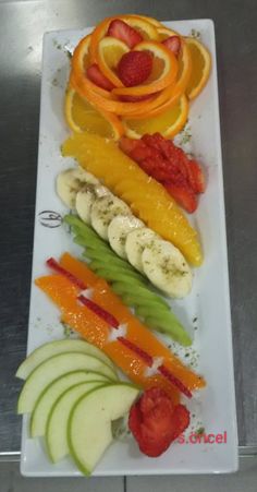 sliced fruits and vegetables arranged on a white plate