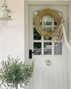 a white door with a wreath on it and a potted plant next to it