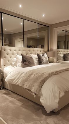 a large bed sitting in the middle of a bedroom next to two mirrors on the wall