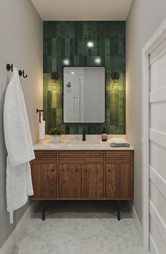 a bathroom with green tiled walls and wooden cabinetry, along with a white towel hanging on the wall