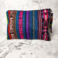 A true work of art, each Corte Cosmetic Bag is lovingly crafted on a traditional pedal loom with the same vibrant fabrics that fashion the iconic skirts of Guatemalan women. This results in an exclusive and one-of-a-kind product that will add a touch of luxury and culture to your collection. Each one has enough space to hold all of your needs, from makeup to brushes to nail polish and more! As always, Handmade and Fair Trade! 9" H x 6" W Brightly lined with nylon Zipper pull-tab 100% cotton Asso Multicolor Travel Pouch Cosmetic Bag, Multicolor Travel Cosmetic Pouch, Bohemian Fabric Travel Bag, Bohemian Travel Bags In Fabric, Multicolor Woven Pouch Clutch, Bohemian Fabric Bag With Rectangular Shape, Bohemian Fabric Bags With Rectangular Shape, Bohemian Fabric Rectangular Bag, Bohemian Rectangular Fabric Bag