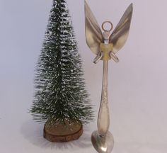 a small christmas tree next to a metal angel ornament