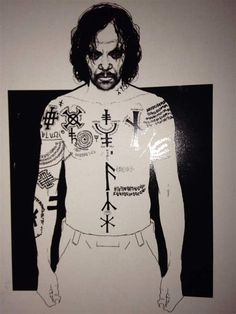 a man with tattoos on his chest standing in front of a wall