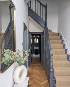 an entry way with stairs, mirror and potted plant