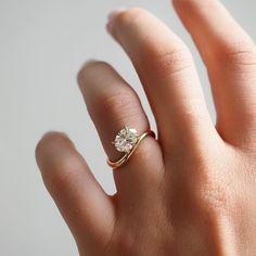 a woman's hand with a diamond ring on top of her finger, showing the side view