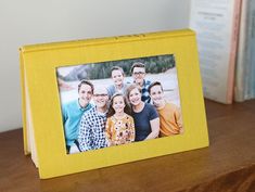 a yellow photo frame sitting on top of a wooden table