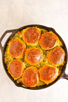 an overhead view of some food in a skillet on a white table with a spoon