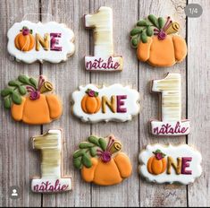 decorated cookies are arranged in the shape of pumpkins and one is number one, on a wooden table