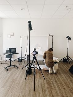 a person sitting on the floor in front of a camera set up for a photo shoot