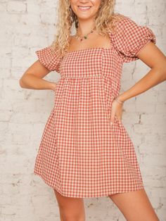 Our Nora Checkered Dress is a sweet babydoll style that brings a playful touch to any outfit with its rust checkered print and square neckline. The short elastic bubble sleeves add a charming detail, perfect for an outdoor fall wedding or event. Style it with ankle booties and a wide-brimmed hat for a cute, carefree look! Details Square Neck Short Elastic Bubble Sleeves Rust Checkered Print Hidden Back Zipper with Hook & Eye Closure Babydoll Style Mini Length Partially Lined Size recs: 2-4 Small, 4-6 Medium, 8-10 Large Provides no stretch Model is 5'8" wearing a size Small Quilted Outerwear, Outdoor Fall Wedding, Fall Wedding Guest, Brimmed Hat, Checkered Print, Checkered Dress, Checker Print, Wedding Guest Looks, Babydoll Style