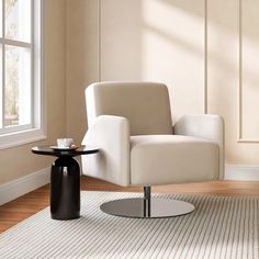 a living room with a white chair and black table on the floor in front of a window