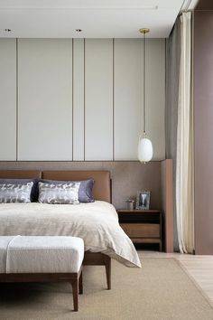 a large bed sitting in the middle of a bedroom next to a wall mounted lamp