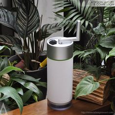 a white and gray device sitting on top of a wooden table next to green plants